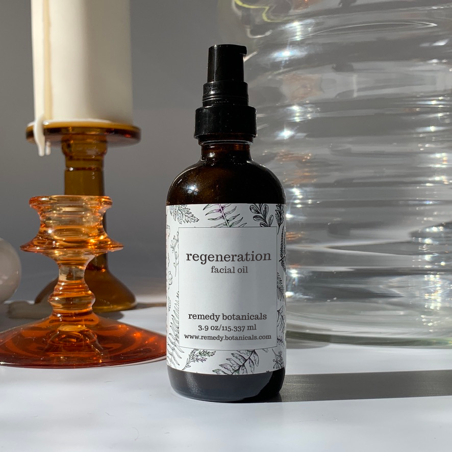 A bottle of regeneration facial oil standing beside a candle.